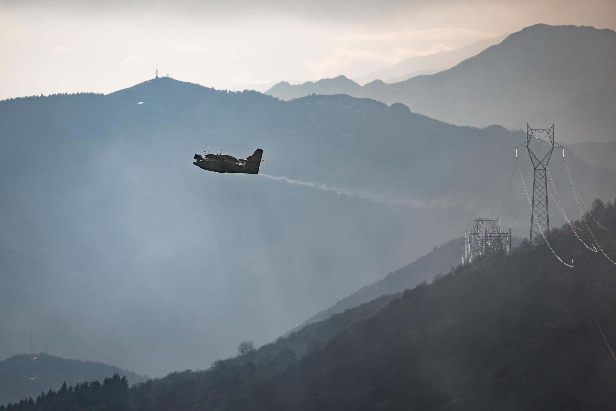Ein italienisches Flugzeug des Typs Canadair bei den Loescharbeiten in den Huegeln von Gambarogno bei Indemini am Lago Maggiore am Dienstag, 1. Februar 2022. Bei den Loescharbeiten kommen nun auch zwei Loeschflugzeuge aus Italien zum Einsatz. Die Flammen wueteten demnach am Montag auf einer Flaeche von etwas mehr als sechs Hektaren. Die Feuerwehr werde mehrere Tage brauchen, um den Brand einzudaemmen, schaetzte gleichentags die Tessiner Kantonspolizei. (KEYSTONE/Ti-Press/Massimo Piccoli)