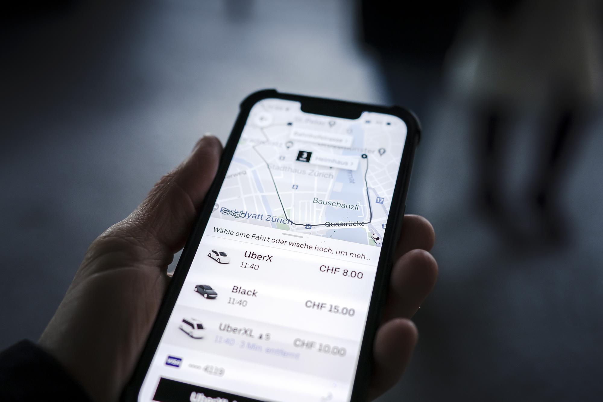 Ein Mann haelt ein Smartphone mit der Fahrdienst App Uber in Zuerich, am Donnerstag, 6. Januar 2022..Das Zuercher Sozialversicherungsgericht gelangt in mehreren Urteilen zum Schluss, dass zwischen dem Fahrdienst Uber und seinen Fahrern ein Anstellungsverhaeltnis besteht und das Unternehmen damit auch Sozialversicherungsbeitraege abliefern muss. (KEYSTONE/Michael Buholzer)