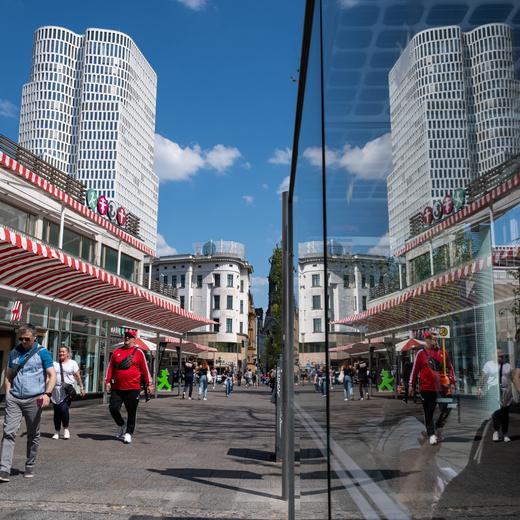 12.05.2023, Berlin, Deutschland, Europa - Eine Strassenszene mit Fussgaengern auf dem Kurfuerstendamm am Kranzler Eck in der City West im Bezirk Charlottenburg-Wilmersdorf. Im Hintergrund sieht man den Turm des Upper West Hochhaus, welcher sich in der Glasscheibe einer Bushaltestelle spiegelt.