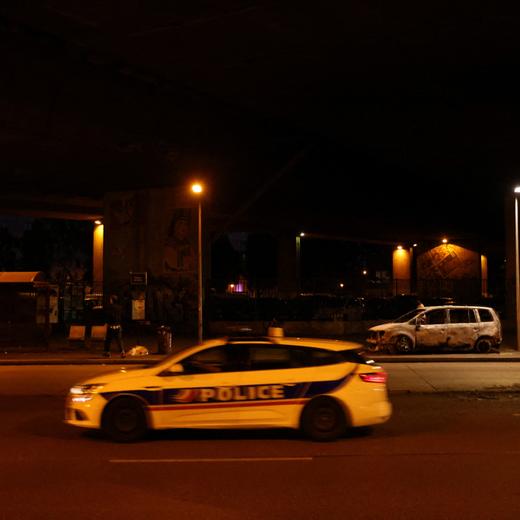 Une voiture de police passe devant un véhicule qui a été incendié. Bondy, 3 juillet 2023.