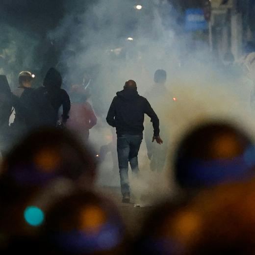 Demonstrators run as French police officers use tear gas in Paris on July 2, 2023, five days after a 17-year-old man was killed by police in Nanterre, a western suburb of Paris. French police arrested 1311 people nationwide during a fourth consecutive night of rioting over the killing of a teenager by police, the interior ministry said on July 1, 2023. France had deployed 45,000 officers overnight backed by light armoured vehicles and crack police units to quell the violence over the death of 17-year-old Nahel, killed during a traffic stop in a Paris suburb on June 27, 2023. (Photo by Ludovic MARIN / AFP)