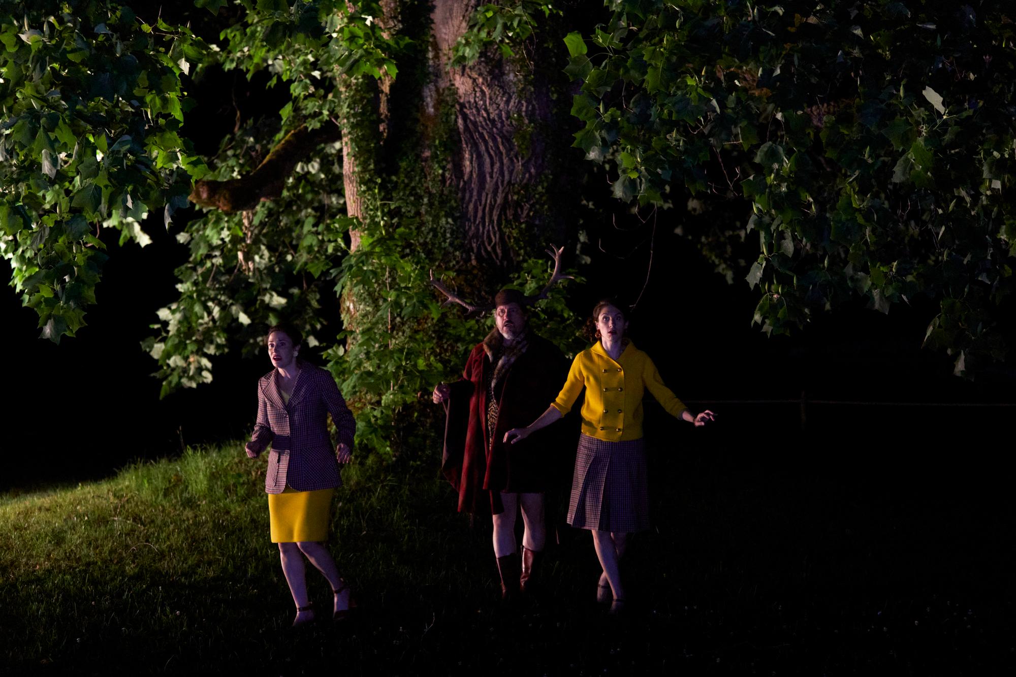 Dans la pénombre, Falstaff (François Nadin), déguisé en cerf, espère encore séduire et trousser Mrs Page (Rachel Gordy) et Mrs Ford (Léonie Keller).