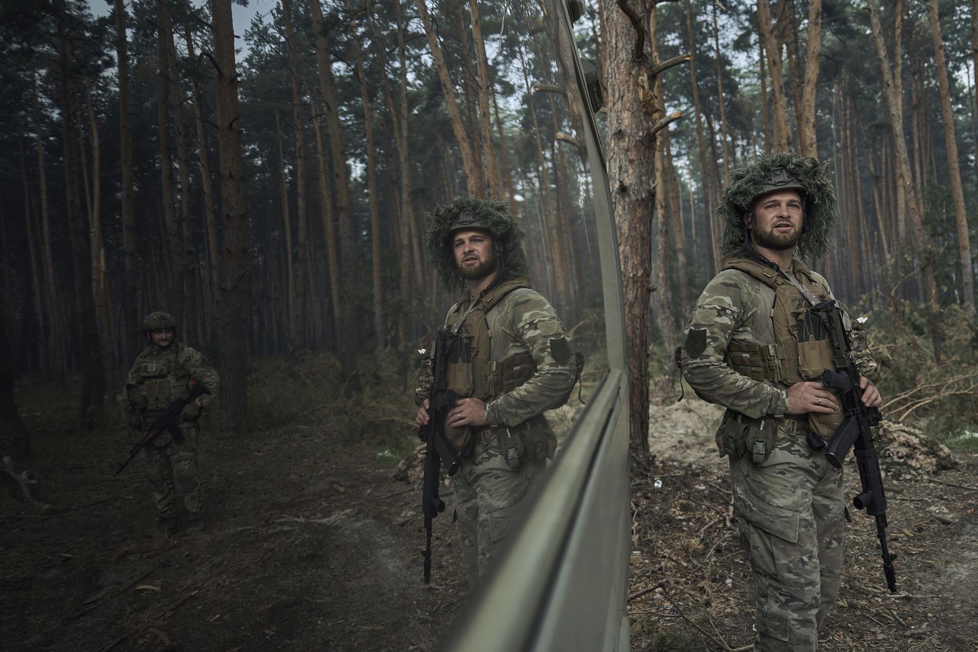 A Ukrainian policeman of special police unit looks on as he is reflected on a window, at the front line, near Kreminna, Luhansk region, Ukraine, Friday, July 7, 2023. (AP Photo/Libkos)