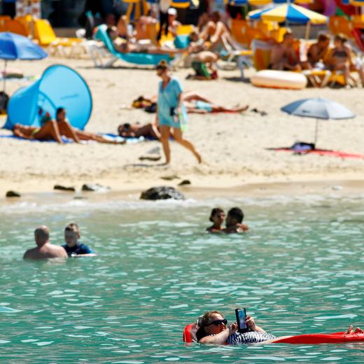 A tourist sunbathes on an air mattress with her phone on the Amadores beach, amid the outbreak of the coronavirus disease (COVID-19) in the south of the island of Gran Canaria, Spain, August 3, 2021. REUTERS/Borja Suarez