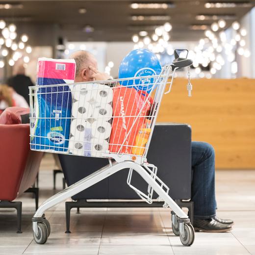 Ein Kunde sitzt hinter seinem vollen Einkaufswagen im Begegnungsbereich und betrachtet sein Mobiltelefon, im Einkaufszentrum Glattzentrum in Wallisellen, Kanton Zuerich, aufgenommen am 26. Februar 2020. (KEYSTONE/Goran Basic)