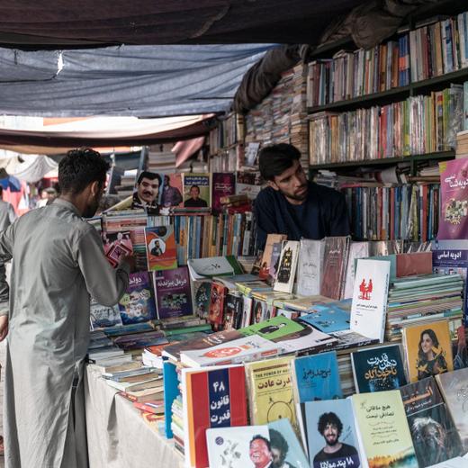 Afghan people scroll through books at a bookshop along a road in Kabul on June 27, 2023. (Photo by Wakil KOHSAR / AFP)