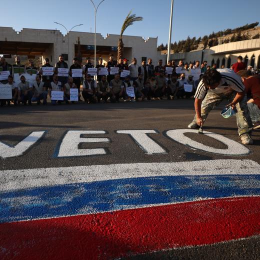 Des activistes syriens peignent un drapeau russe et le mot « veto » pour protester contre la décision de la Russie de faire cesser l'aide humanitaire dans la région d'Idlib.