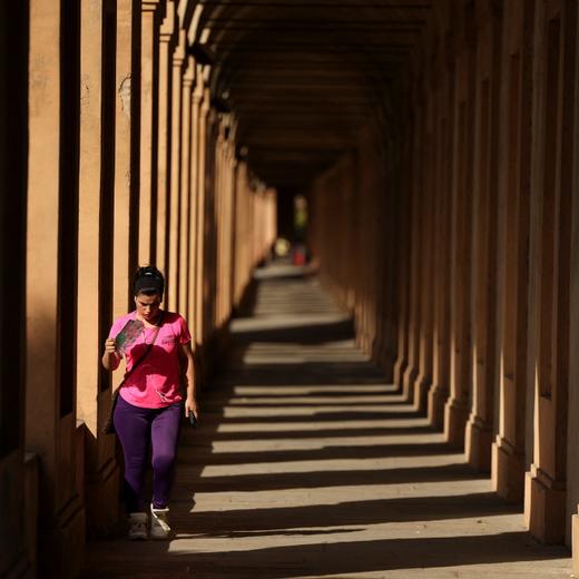 A woman uses a fan as she walks during a heatwave, as temperatures are expected to rise further in the coming days, in Bologna, Italy July 18, 2023. REUTERS/Claudia Greco