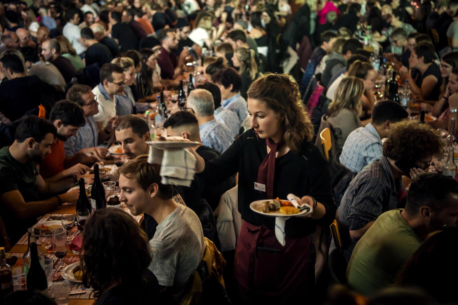 Une serveuse sert aux convives les Atriaux avec salade de carottes cuites et roestis de la Saint-Martin lors de la fete jurassienne du cochon le dimanche 14 novembre 2021 a la halle polyvalente de Chevenez dans l'Ajoie. La fete de la Saint-Martin se celebre le deuxieme week-end du mois de novembre. Sa tradition remonte a tres loin. Quand les travaux des champs etaient termines, les paysans tuaient le cochon pour marquer la fin de la saison. Ils conservaient les morceaux qu'ils pouvaient fumer et consommaient toutes les autres parties de la bete. (KEYSTONE/Jean-Christophe Bott)