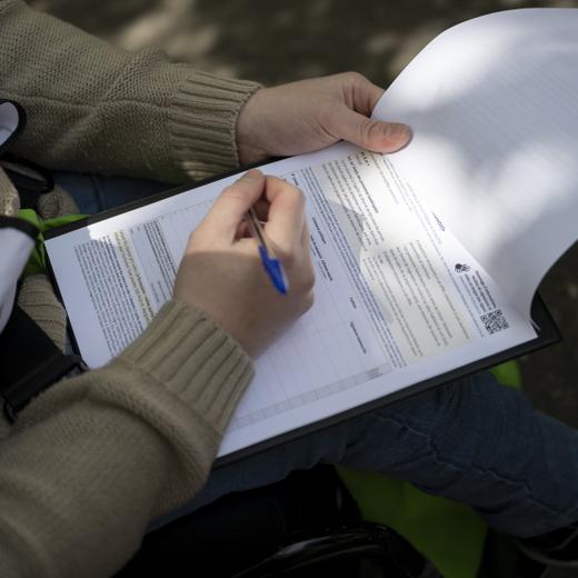 Eine Person unterzeichnet eine Sammelliste an der ersten Sammelaktion kurz vor einer Medienkonferenz zur Lancierung der eidgenoessischen Volksinitiative "Fuer die Gleichstellung von Menschen mit Behinderungen (Inklusions-Initiative)", am Donnerstag, 27. April 2023 in Bern. (KEYSTONE/Anthony Anex)