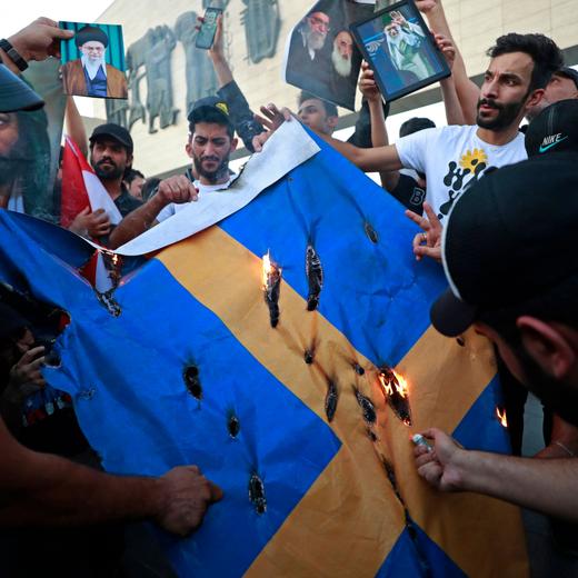 Des partisans de l'ex-groupe paramilitaire Hashd al-Shaabi brûlent un drapeau suédois lors d'une manifestation à la place Tahrir à Bagdad. Le 20 juillet 2023.