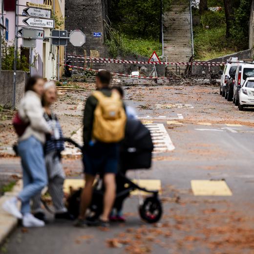 Des personnes regardent les debris dans une rue, un jour apres passage de la forte tempête, le 25 juillet 2023, à La Chaux-de-Fonds. (KEYSTONE/Jean-Christophe Bott)