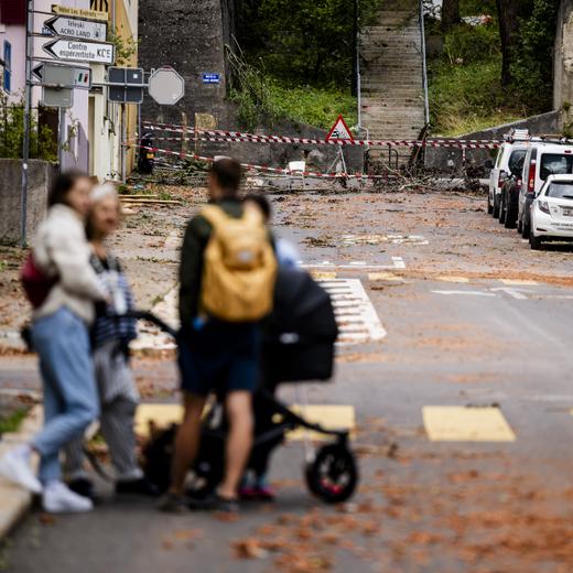 Des personnes regardent les debris dans une rue, un jour apres passage de la forte tempête, le 25 juillet 2023, à La Chaux-de-Fonds. (KEYSTONE/Jean-Christophe Bott)