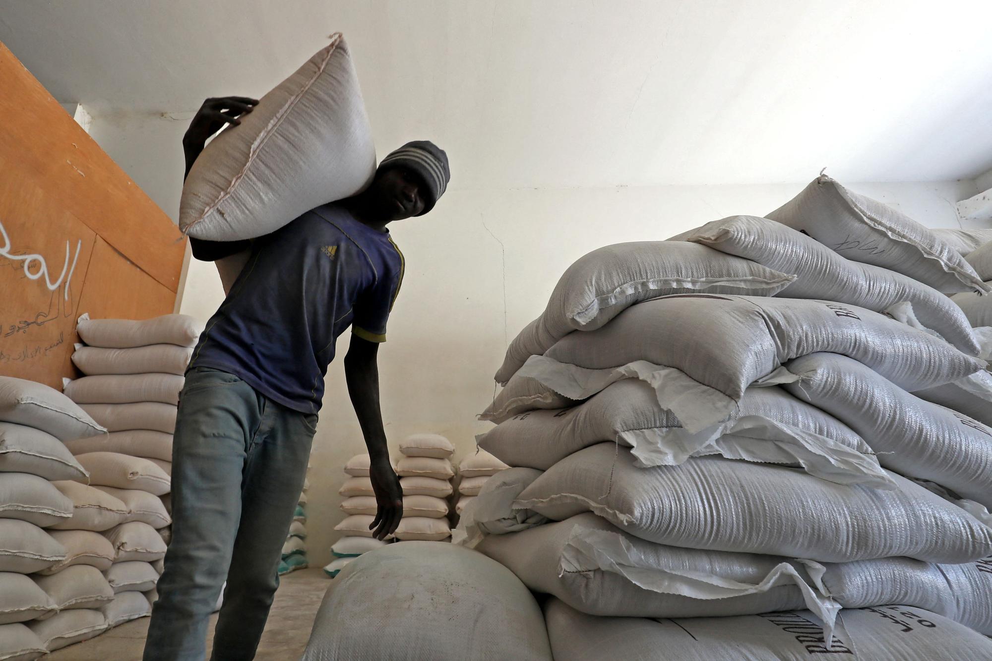 A worker carries a bag of flour at a grain market in Libya's capital Tripoli on July 22, 2023. Russia issued a veiled warning over the future of grain exports via the Black Sea after refusing to extend a key agreement allowing safe passage for cargo ships from Ukrainian ports. (Photo by Mahmud Turkia / AFP)