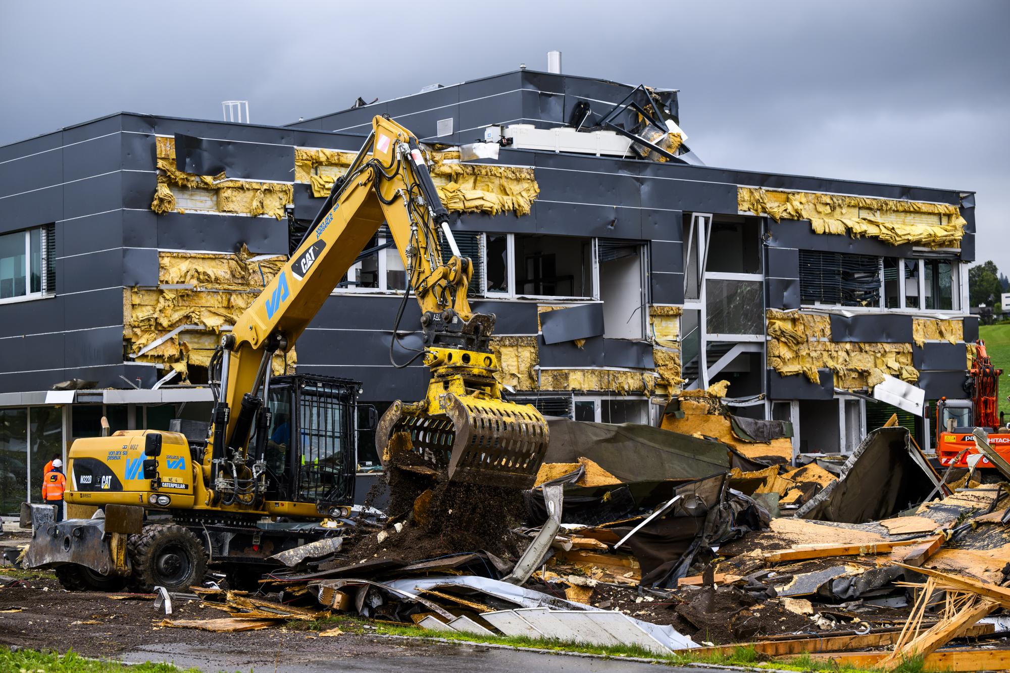 Des ouvriers enlevent les debris entre l'entreprise Sellita Watch et l'entreprise La Semeuse, un jour apres le passage de la forte tempete le mardi 25 juillet 2023 au Cret-du-Locle a cote de La Chaux-de-Fonds. Le deblaiement des materiaux et la reparation des infrastructures ont repris mardi a La Chaux-de-Fonds dans le canton de Neuchatel, apres la violente tempête de la veille. (KEYSTONE/Jean-Christophe Bott)