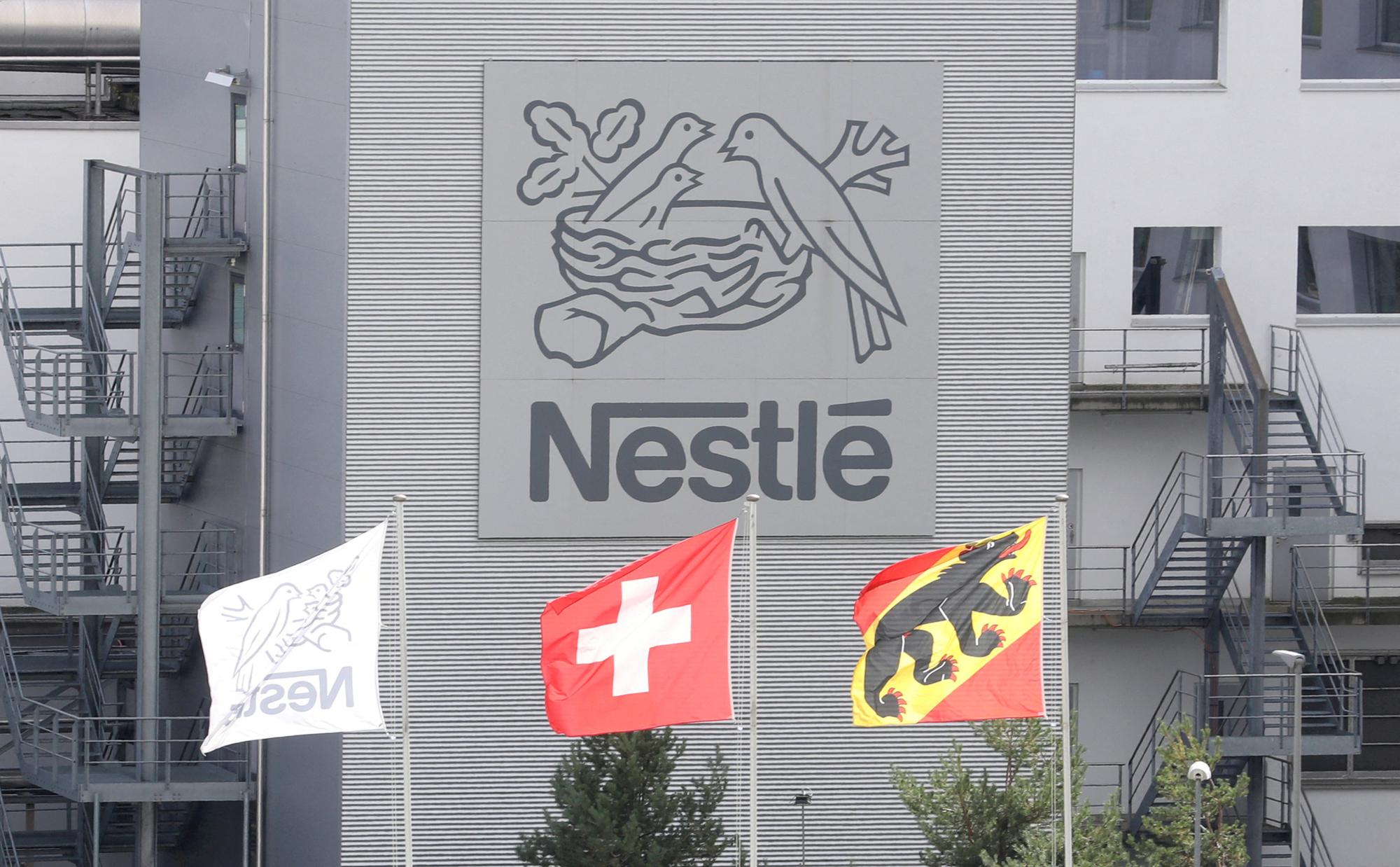 FILE PHOTO: A Swiss national flag flies beside a flag of the canton of Bern in front of the logo of Nestle at a plant in Konolfingen, Switzerland September 28, 2020. REUTERS/Arnd Wiegmann//File Photo