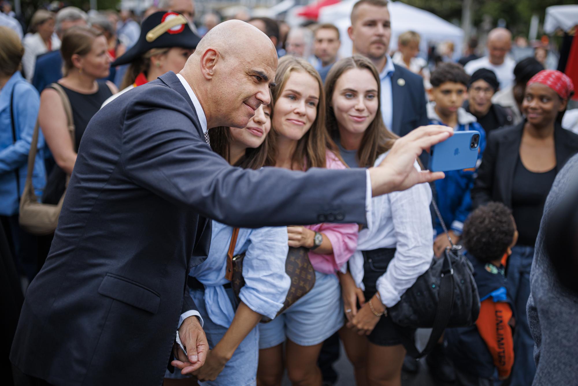 Le president de la Confederation Alain Berset realise une selfie lors d'un bain de foule alors qu'il participe aux festivites de la fete nationale ce mardi 1 aout 2023 a Lausanne. (KEYSTONE/Valentin Flauraud)