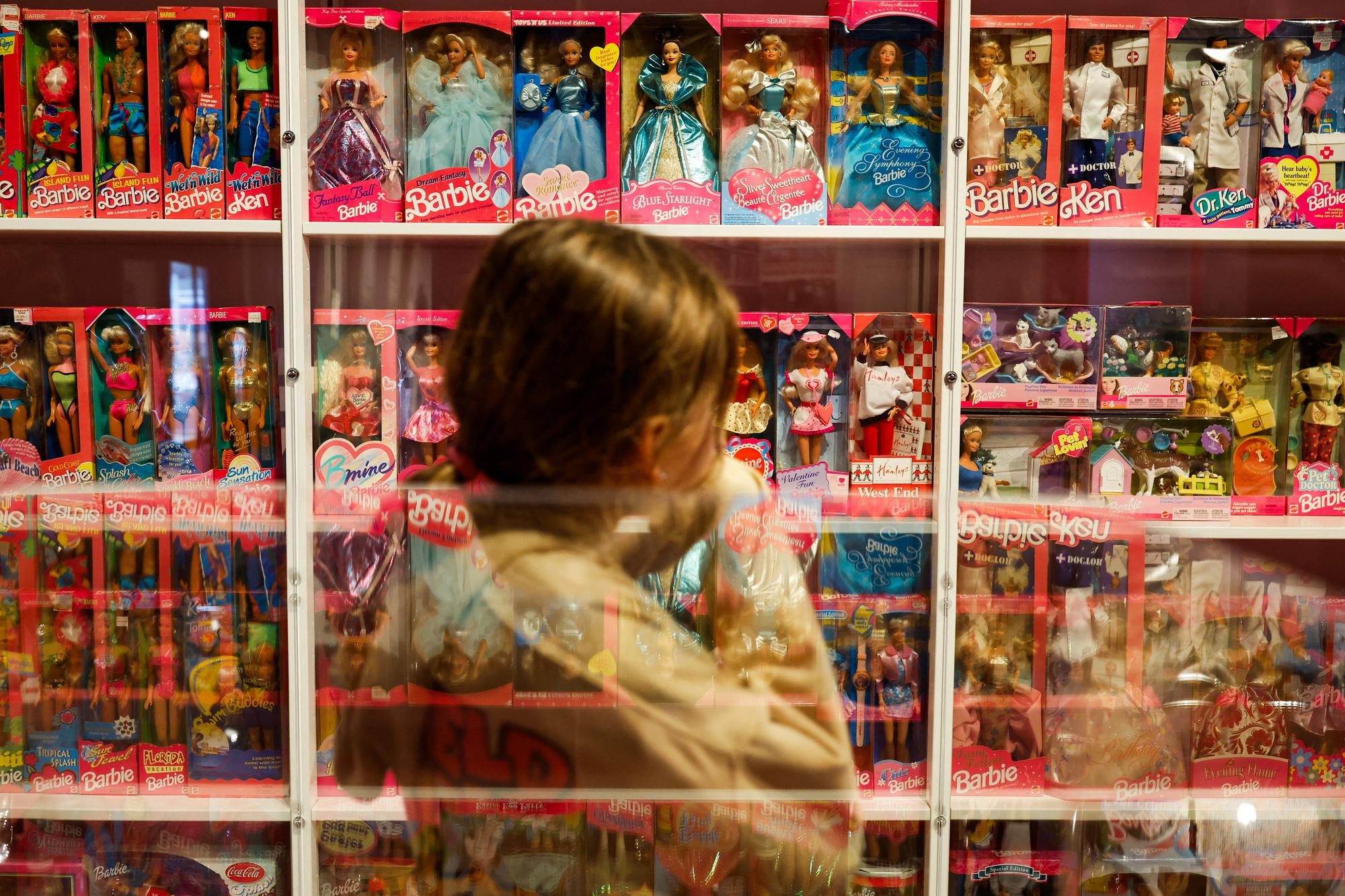 A girl looks at Barbie dolls as they are reflected on the glass in The Barbie Collector exhibition at The Wellington Museum, in Wellington, New Zealand July 31, 2023. REUTERS/Amanda Perobelli