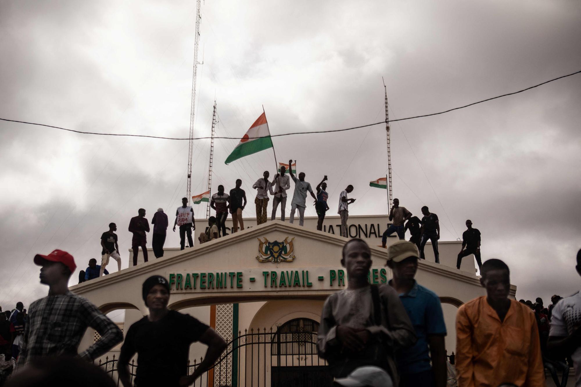 Protesters hold a Niger flag during a demonstration on independence day in Niamey on August 3, 2023. Hundreds of people backing the coup in Niger gathered on August 3, 2023 for a mass rally in the capital Niamey with some brandishing giant Russian flags.  The demonstrators converged at Concertation Square in the heart of the city, following a call by a coalition of civil society associations on a day marking the country's 1960 independence from France. (Photo by AFP)