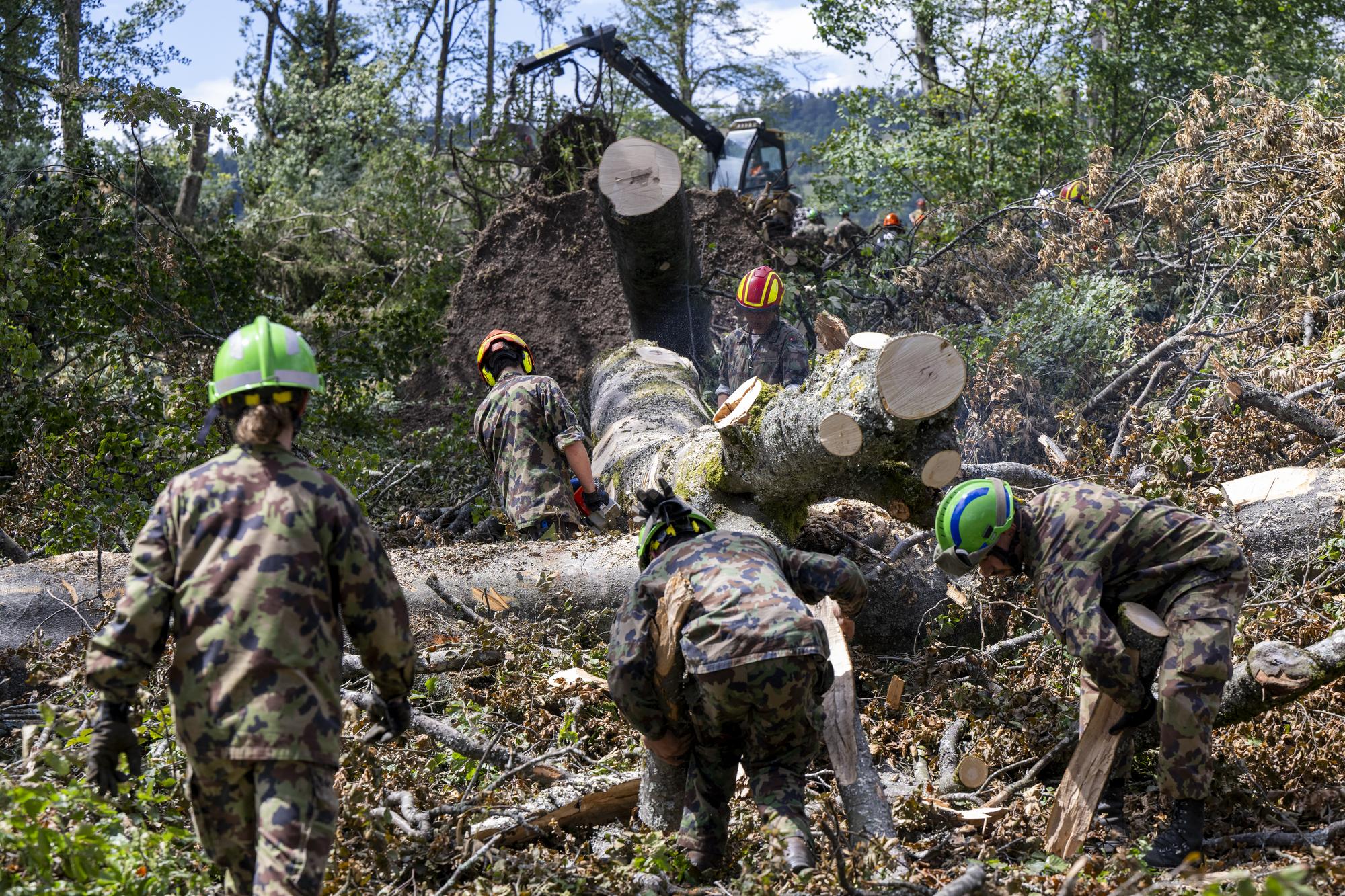 Des militaires de l'armee suisse effectuent des travaux de bucheronnage pres d'une ecole ou les degats sont encore visibles en ville de la Chaux-de-Fonds, lors d'une visite de terrain et apres une conference de presse des autorites cantonales neuchateloises et communales chaux-de-fonnieres dix jours apres la tempete qui a frappe les Montagnes neuchateloises, ce jeudi 3 aout 2023 a La Chaux-de-Fonds , et ainsi faire le point de la situation et les interventions en cours lors d'une visite de terrain. (KEYSTONE/Martial Trezzini)