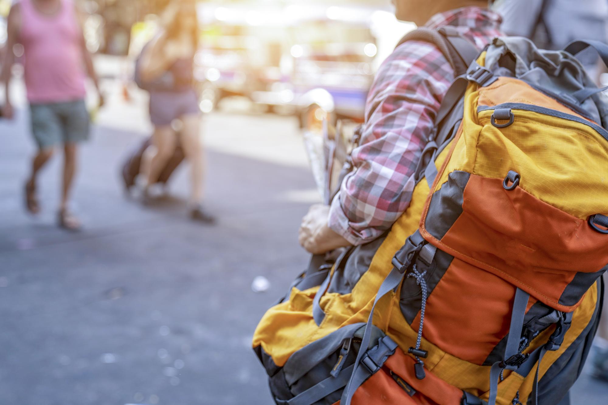 Young male backpacker walking in a famous street night market in Asia