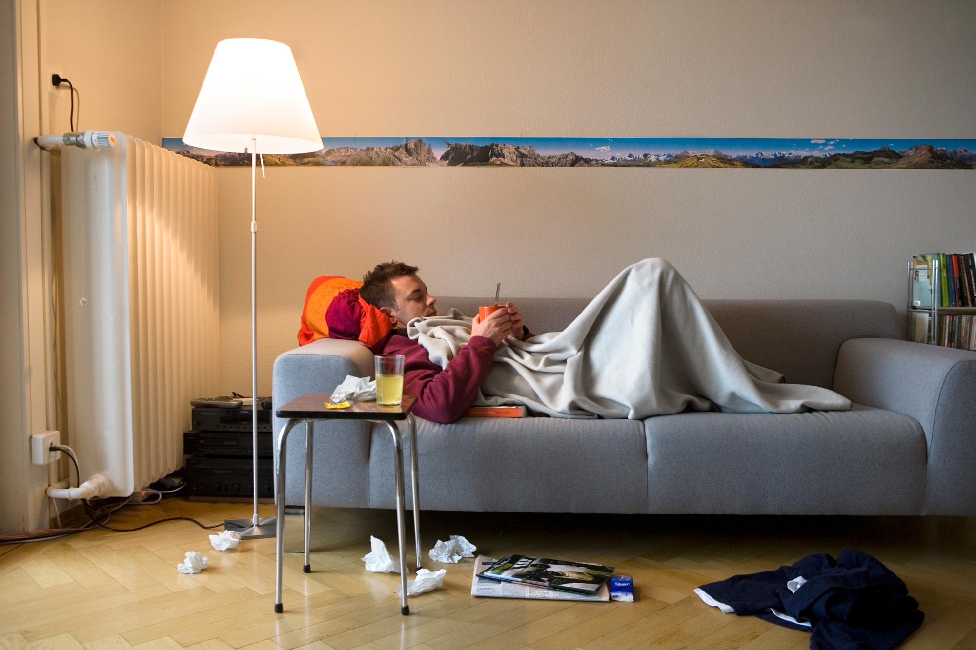 [Themenbild Grippe, gestellte Aufnahme] Ein Mann, der erkrankt ist, liegt mit einer Tasse Tee auf dem Sofa, aufgenommen am 27. Oktober 2007 in Zuerich. Daneben auf dem Hocker steht ein Glas mit einem Medikament in fluessiger Form. (KEYSTONE/Martin Ruetschi) [Themed picture of influenza, posed picture] A sick man lies with a cup of tea on a sofa, pictured in Zurich, Switzerland, on October 27, 2007. A glass with a liquid medicine is placed next to him on a taboret. (KEYSTONE/Martin Ruetschi)