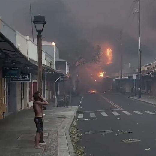 People watch as smoke and flames fill the air from raging wildfires on Front Street in downtown Lahaina, Maui on Tuesday, Aug. 8, 2023. Maui officials say wildfire in the historic town has burned parts of one of the most popular tourist areas in Hawaii. County of Maui spokesperson Mahina Martin said in a phone interview early Wednesday says fire was widespread in Lahaina, including Front Street, an area of the town popular with tourists. (Alan Dickar via AP