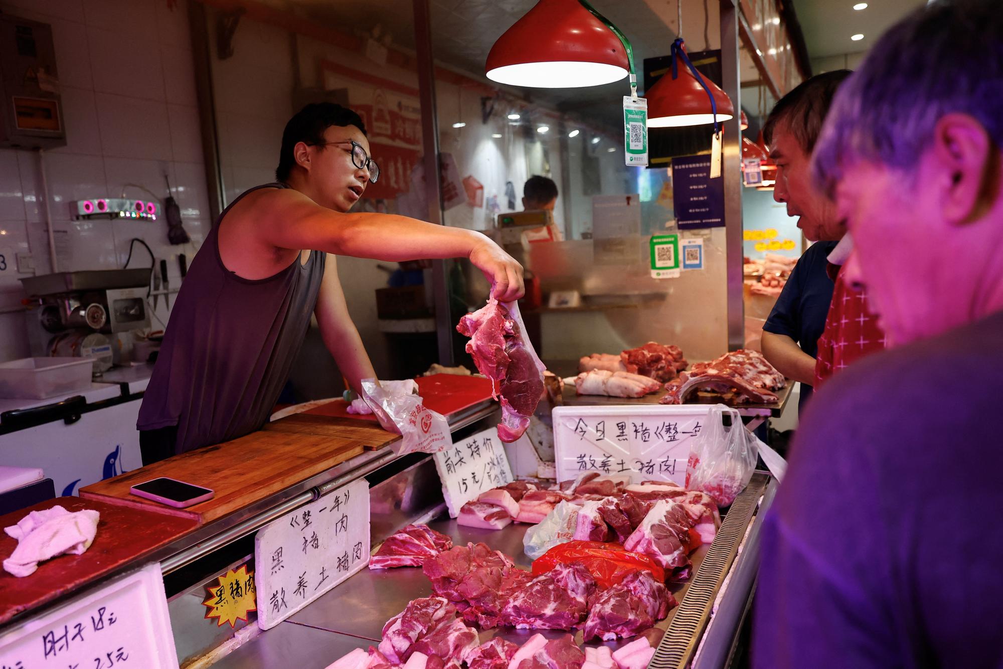 A pork vendor attends to a customer at a morning market in Beijing, China August 9, 2023. REUTERS/Tingshu Wang