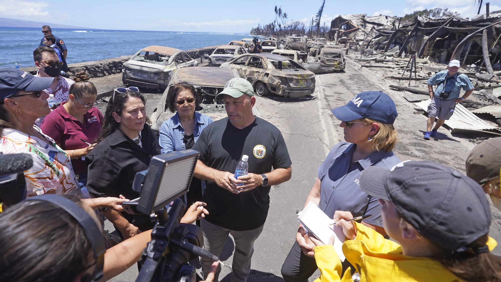 Hawaii Gov. Josh Green, center, speaks to reporters during a tour of wildfire damage on Saturday, Aug. 12, 2023, in Lahaina, Hawaii. (AP Photo/Rick Bowmer)  Josh Green