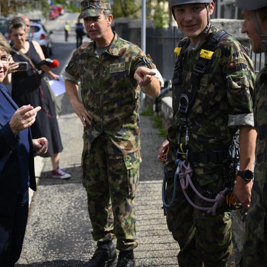 La conseillere federale Viola Amherd, gauche, parle avec des soldats lors de la visite des troupes de l'Armee Suisse engagees apres la tempete qui a frappe les Montagnes neuchateloises ce mardi 15 aout 2023 a La Chaux-de-Fonds. (KEYSTONE/Laurent Gillieron)