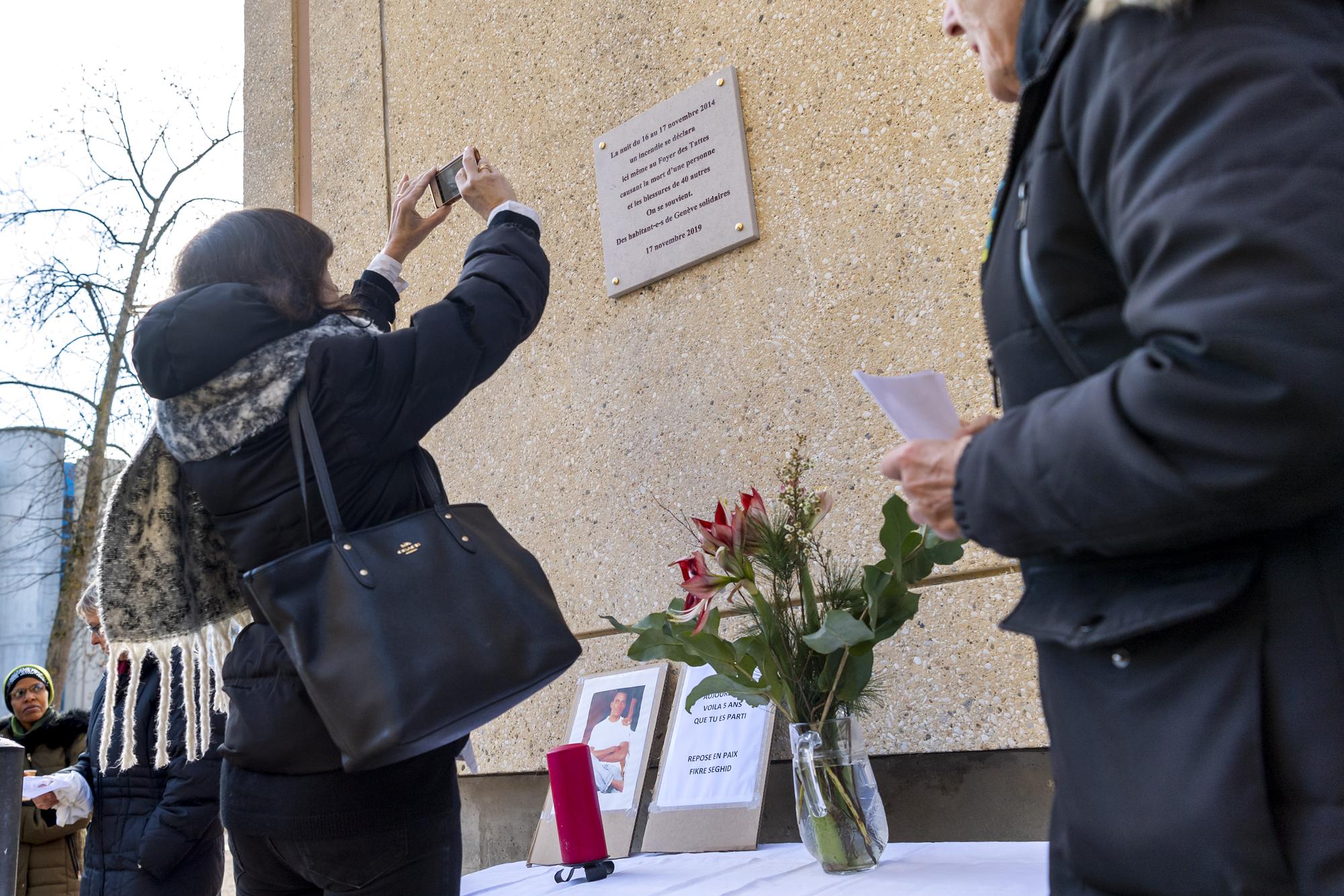 Des personnes assistent a la ceremonie, lors d'un moment de recueillement et a l'inauguration de la plaque commemorant l'incendie qui s'est deroule dans la nuit du 16 au 17 novembre 2014 au Bat I du Foyer des Tattes centre de requerants d'asile. L'incendie du centre des Tattes avait fait un mort et une quarantaine de blesses, dont onze graves. La justice genevoise a ouvert une enquete sur ce drame. (KEYSTONE/Martial Trezzini)
