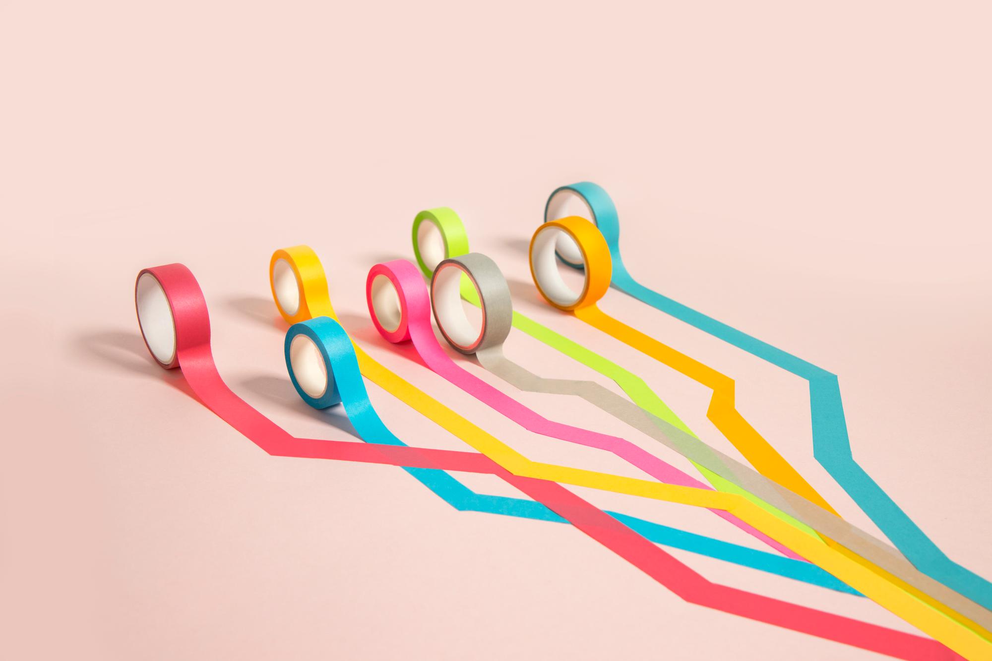 Group of multi coloured tape rolling out together towards one direction from one single point.