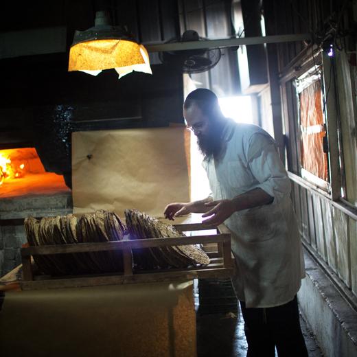 An ultra-Orthodox Jewish man collects the baked Matzoth (unleavened bread) on March 24 2014,, in southern Israeli village of Komemiyut near the Israeli town of Kiryat Gat. Religious Jews throughout the world eat matzoth during the eight-day Pesach holiday (Passover), which begins this year on 14 April, to commemorate the Israelites' exodus from Egypt some 3,500 years ago. Due to the haste with which the Jews left Egypt, the bread they had prepared for the journey did not have time to rise. To commemorate their ancestors' plight, religious Jews do not eat leavened food products throughout Passover. AFP PHOTO/Menahem KAHANA (Photo by MENAHEM KAHANA / AFP)