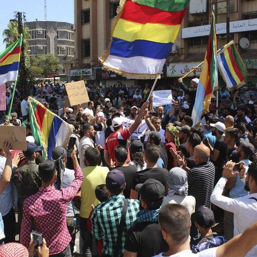 In this photo released on Sunday, Aug. 27, 2023, by Suwayda24, people stage a protest as they wave the Druze flags in the southern city of Sweida, Syria. Anti-government protests have rocked south Syria for the past week. Demonstrators initially took to the streets over surging inflation but are now calling for the ouster of President Bashar Assad, echoing the beginnings of a 2011 uprising that sparked Syria's brutal civil war. (Suwayda24 via AP)