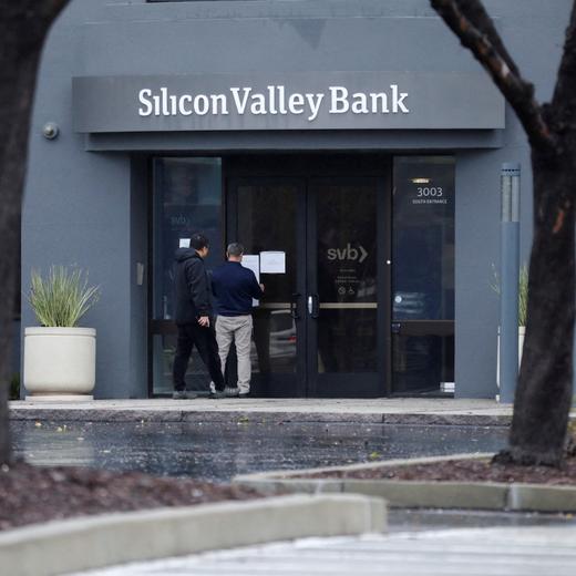 FILE PHOTO: A man puts a sign on the door of the Silicon Valley Bank as an onlooker watches at the bank's headquarters in Santa Clara, California, U.S. March 10, 2023. REUTERS/Nathan Frandino/File Photo