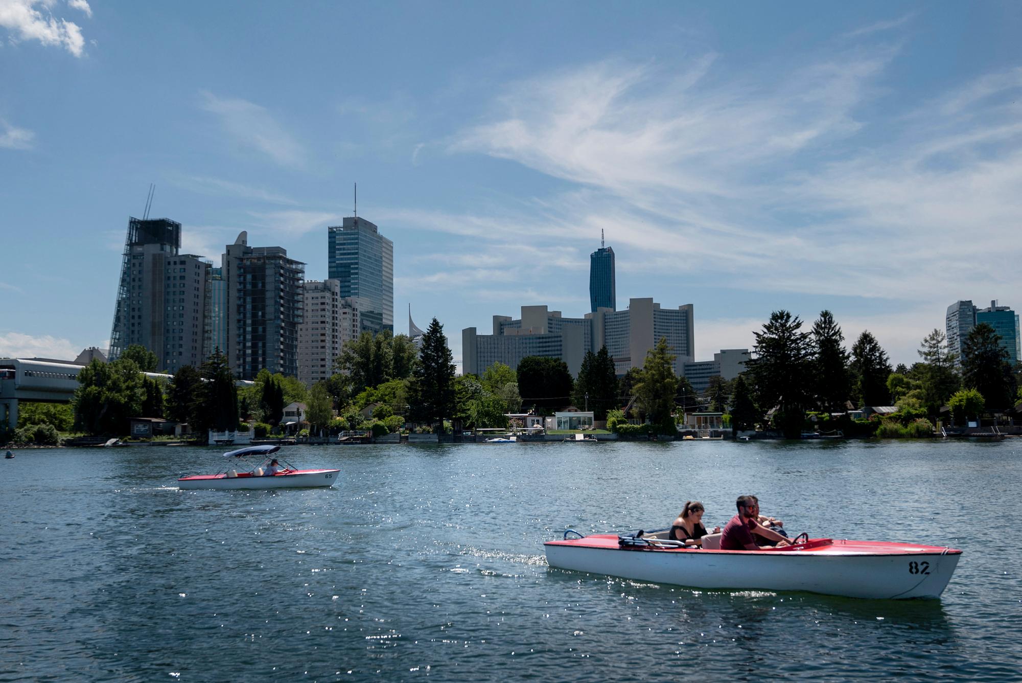 People take a tour with small boats on one of the branches of Danube river, the Old Danube, near the Vienna International Centre in Vienna, Austria, on June 1, 2022. (Photo by JOE KLAMAR / AFP)