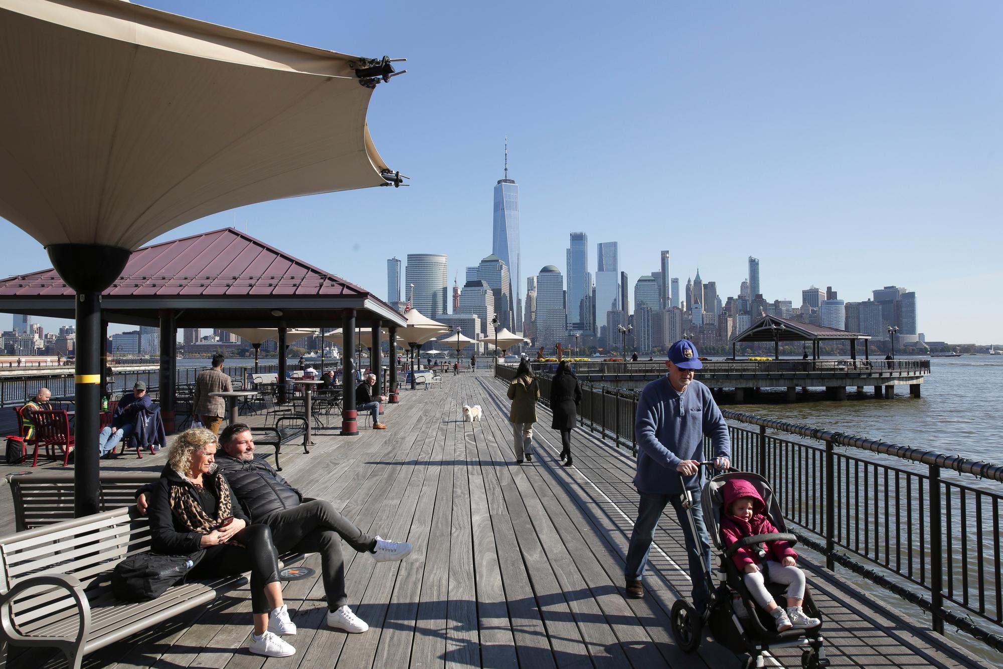 People enjoy the waterfront that overlooks the skyline of lower Manhattan in Jersey City, N.J., Wednesday, Nov. 6, 2019. Voters in the New Jersey city approved restrictions on Airbnb and other short-term rental companies on Tuesday, Nov. 5. (AP Photo/Seth Wenig)