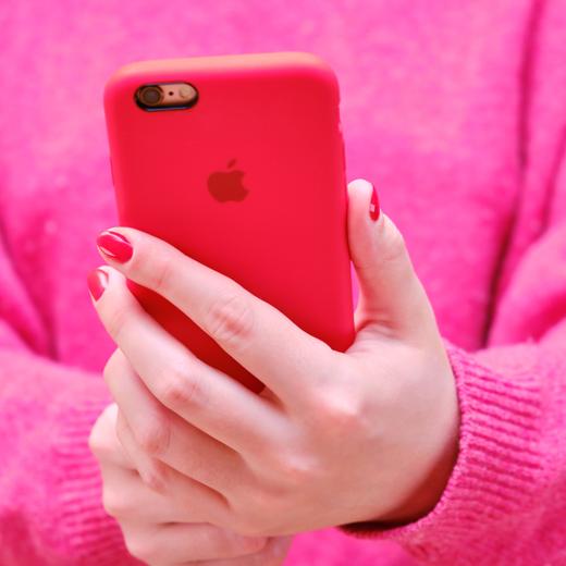Female hands holding the iphone Apple in a red case. The girl holds the phone and takes a selfie photo