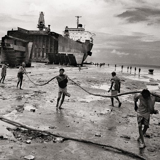 BEI1999020Z00073-21A 001. Dhakin, Shatialbur, Chittagong, Bangladesh © Ian Berry / Magnum Photos  Bare-handed men and boys prepare to drag a hawser in the ship-breaking yard. Huge tankers are driven at full throttle and high tide on to the beach where they are broken up mostly by hand with scant regard for health and safety.