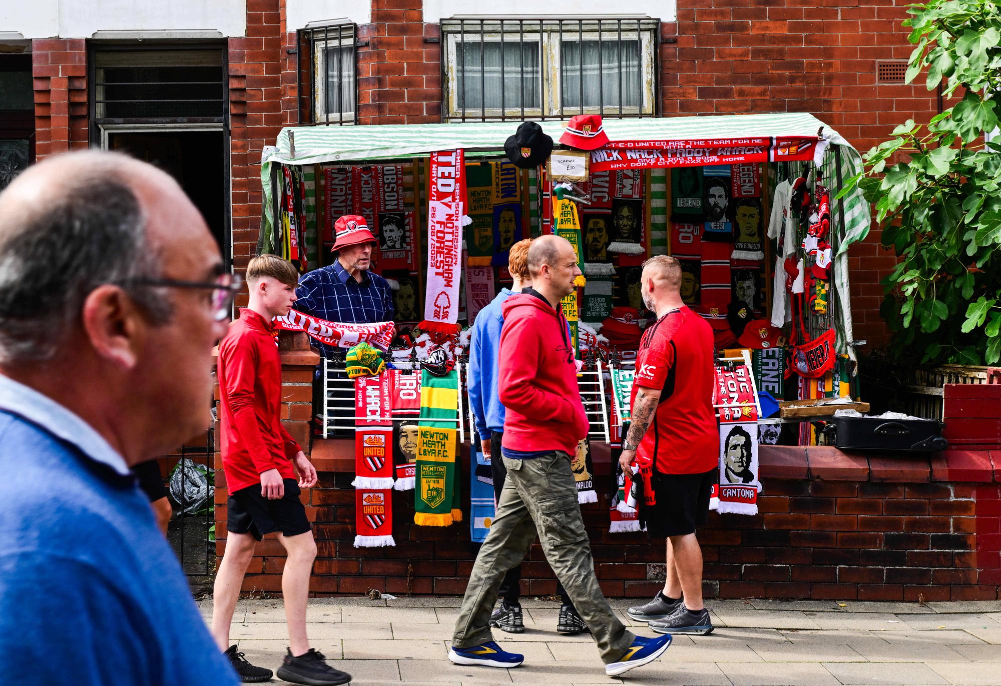 Mandatory Credit: Photo by Greig Cowie/Shutterstock 14067993s A merchandise stall set up in the front Garden of one of the Terraced houses along Sir Matt Busby Way on the way to Old Trafford Stadium, Manchester United, ManU Manchester United v Nottingham Forest, Premier League, Football, Old Trafford, Manchester, UK - 26 Aug 2023 EDITORIAL USE ONLY No use with unauthorised audio, video, data, fixture lists, club/league logos or live services. Online in-match use limited to 120 images, no video emulation. No use in betting, games or single club/league/player publications. Manchester United v Nottingham Forest, Premier League, Football, Old Trafford, Manchester, UK - 26 Aug 2023 EDITORIAL USE ONLY No use with unauthorised audio, video, data, fixture lists, club/league logos or live services. Online in-match use limited to 120 images, no video emulation. No use in betting, games or single club/league/player publications. PUBLICATIONxINxGERxSUIxAUTxHUNxGRExMLTxCYPxROUxBULxUAExKSAxONLY Copyright: xGreigxCowie/Shutterstockx 14067993s