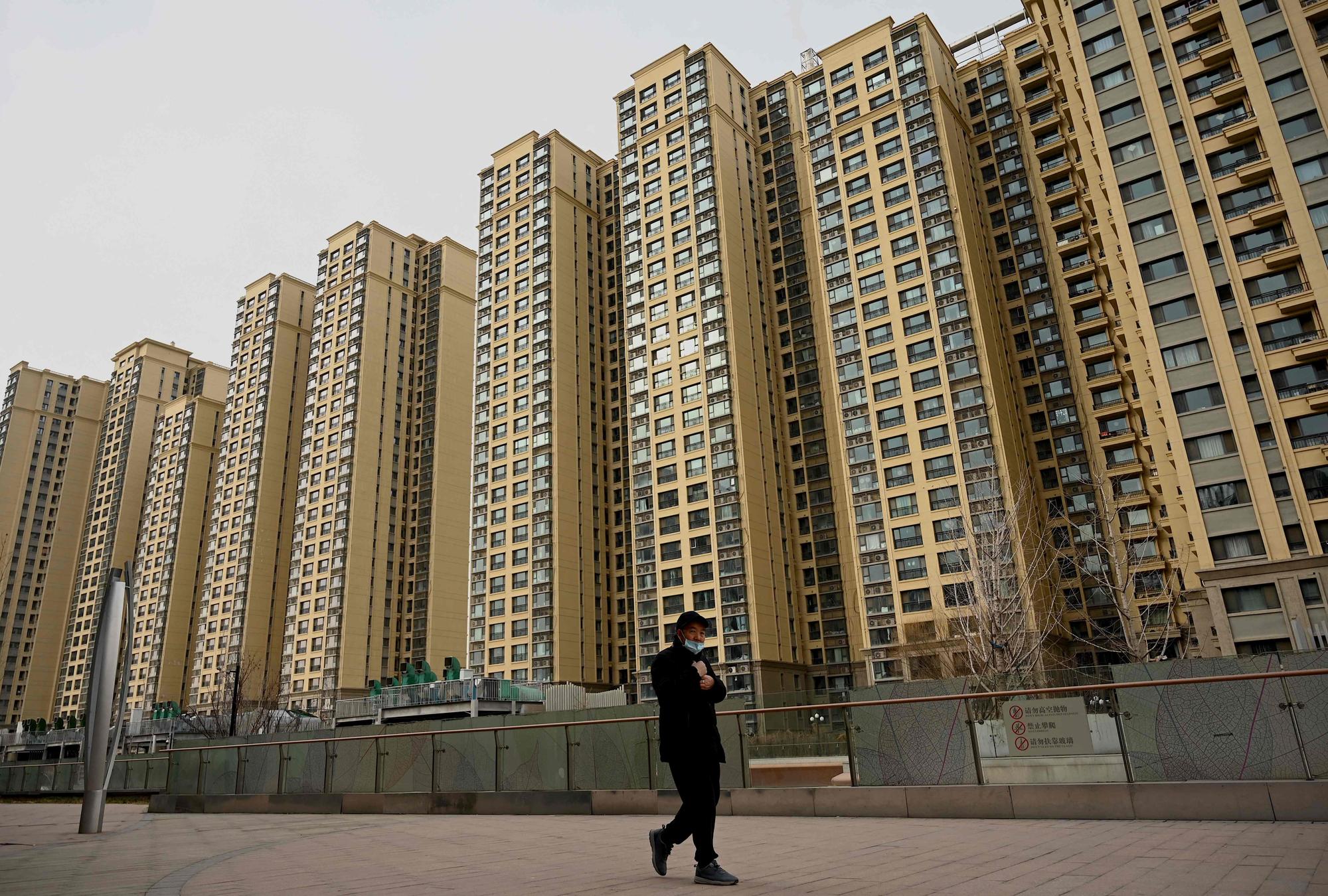 (FILES) A man walks past a housing complex by Chinese property developer Evergrande in Beijing on December 8, 2021. Heavily indebted Chinese property giant Evergrande resumed trading on the Hong Kong Stock Exchange on October 3, 2023, according to a statement on the bourse's website. (Photo by Noel Celis / AFP)