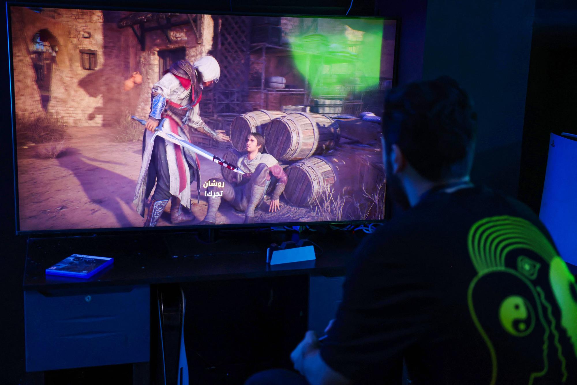 A man plays the newly released video game 'Assassin's Creed Mirage' in a cybercafe in Baghdad on October 4, 2023. After years of turbulence that saw several top executives out the door, Ubisoft is betting aggressively on 'Assassin's Creed Mirage,' set in ninth-century Baghdad during the Abbasid caliphate era, to level up profits for the French publisher with a steadier line-up of new releases. (Photo by Ahmad AL-RUBAYE / AFP)