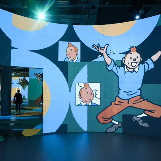 Des journalistes et des invites regardent des projections d'images des albums de Tintin lors d'une conference de presse de l'exposition "Tintin l'aventure immersive" sur le site de Beaulieu le jeudi 12 octobre 2023 a Lausanne. L'aventure immersive est a voir sur une surface de projection de 2'500 metres carres, jusqu'au 11 fevrier 2024, avec plus de 2'000 images issues des 24 albums de Tintin. (KEYSTONE/Jean-Christophe Bott)