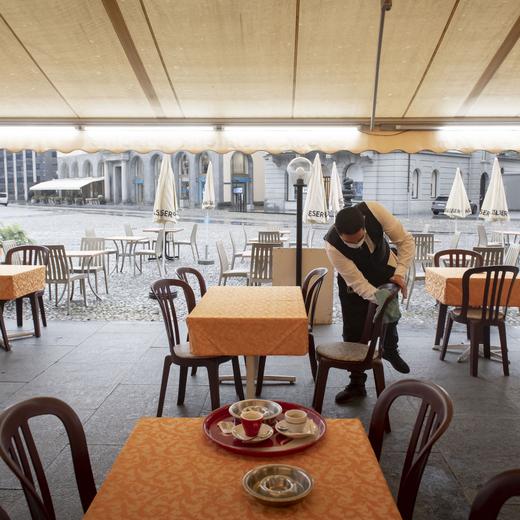 A waiter desinfects chairs at the restaurant Portico on the Piazza Grande in Locarno, Switzerland, Monday, May 11, 2020. Switzerland reopens it's shops, fitness centers, restaurants and museums under strict restrictions for social distancing and hygiene measures today. (KEYSTONE/Ti-Press/Pablo Gianinazzi)
