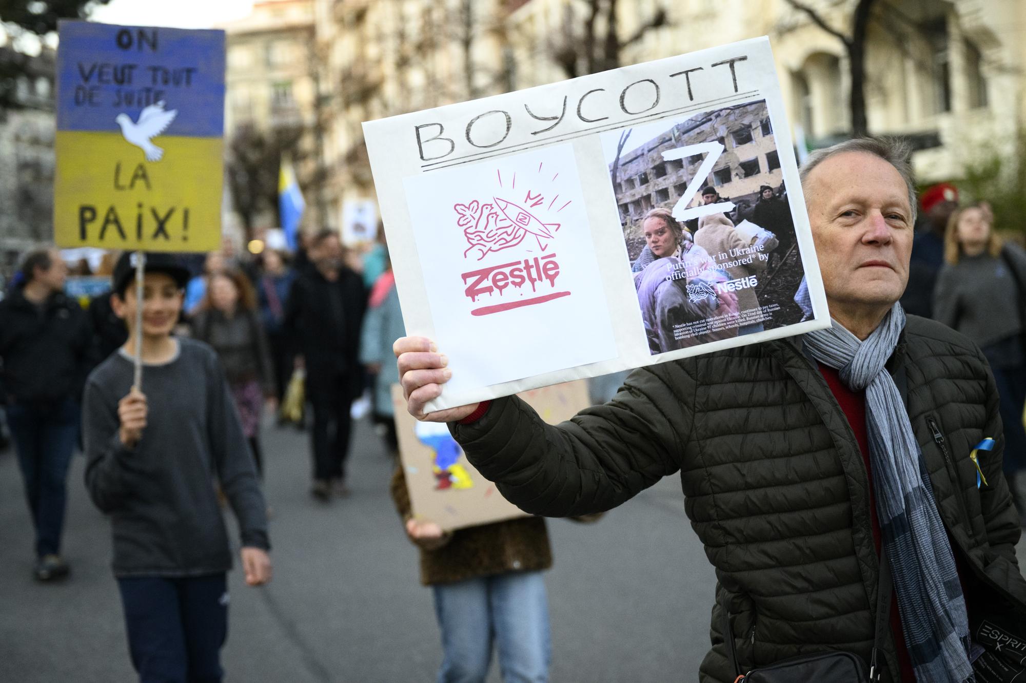 Protestors carry placards with "Boycott Nestle" as they take part in a demonstration against the Russian invasion of Ukraine on the sideline of the Financial Times Commodities Global Summit, in Lausanne, Switzerland, Tuesday, March 22, 2022. Russian troops entered Ukraine on 24 February prompting the country's president to declare martial law and triggering a series of severe economic sanctions imposed by Western countries on Russia. (KEYSTONE/Laurent Gillieron)