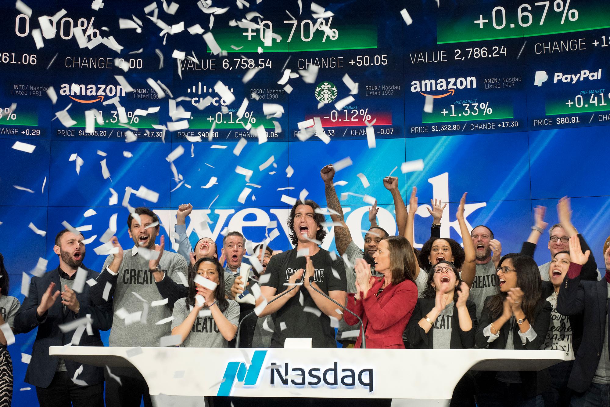 Adam Neumann, center, co-founder and CEO of WeWork, attends the opening bell ceremony at Nasdaq, Tuesday, Jan. 16, 2018, in New York. WeWork is a privately held shared workspace company based in New York. (AP Photo/Mark Lennihan)