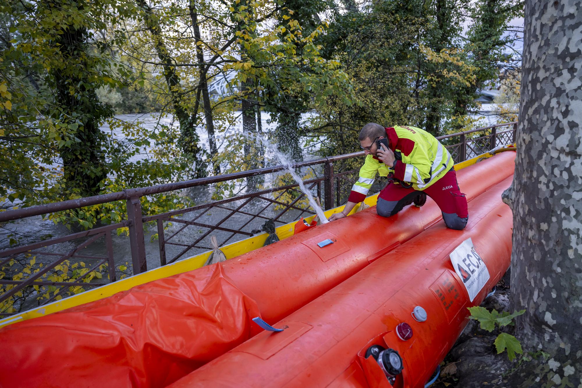 Des pompiers du SIS (Services Incendie et Secours) et ainsi que des pompiers volontaire installent des barrages mobiles le long de l'Arve suite a la montee des eaux de la riviere, ce mercredi 15 novembre 2023 a Geneve. L'Arve fait face a une situation de crue importante. Le debit de la riviere depassait, mardi, 480 m3 par seconde, soit trois fois le debit moyen du mois de novembre. Il pourrait atteindre 600 a 800 m3 par seconde dans la nuit de mardi a mercredi. (KEYSTONE/Martial Trezzini)