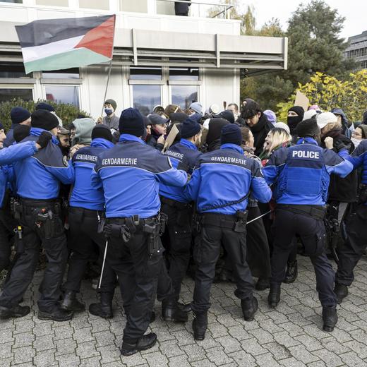 Police scuffle with protesters holding up placards on the situation of the Israel-Hamas war during a demonstration during the visit of French President Emmanuel Macron and Swiss President Alain Berset to the University of Lausanne (UNIL), Switzerland, Thursday, Nov. 16, 2023. Macron is in Switzerland for a two-day visit. (Cyril Zingaro/Keystone via AP)