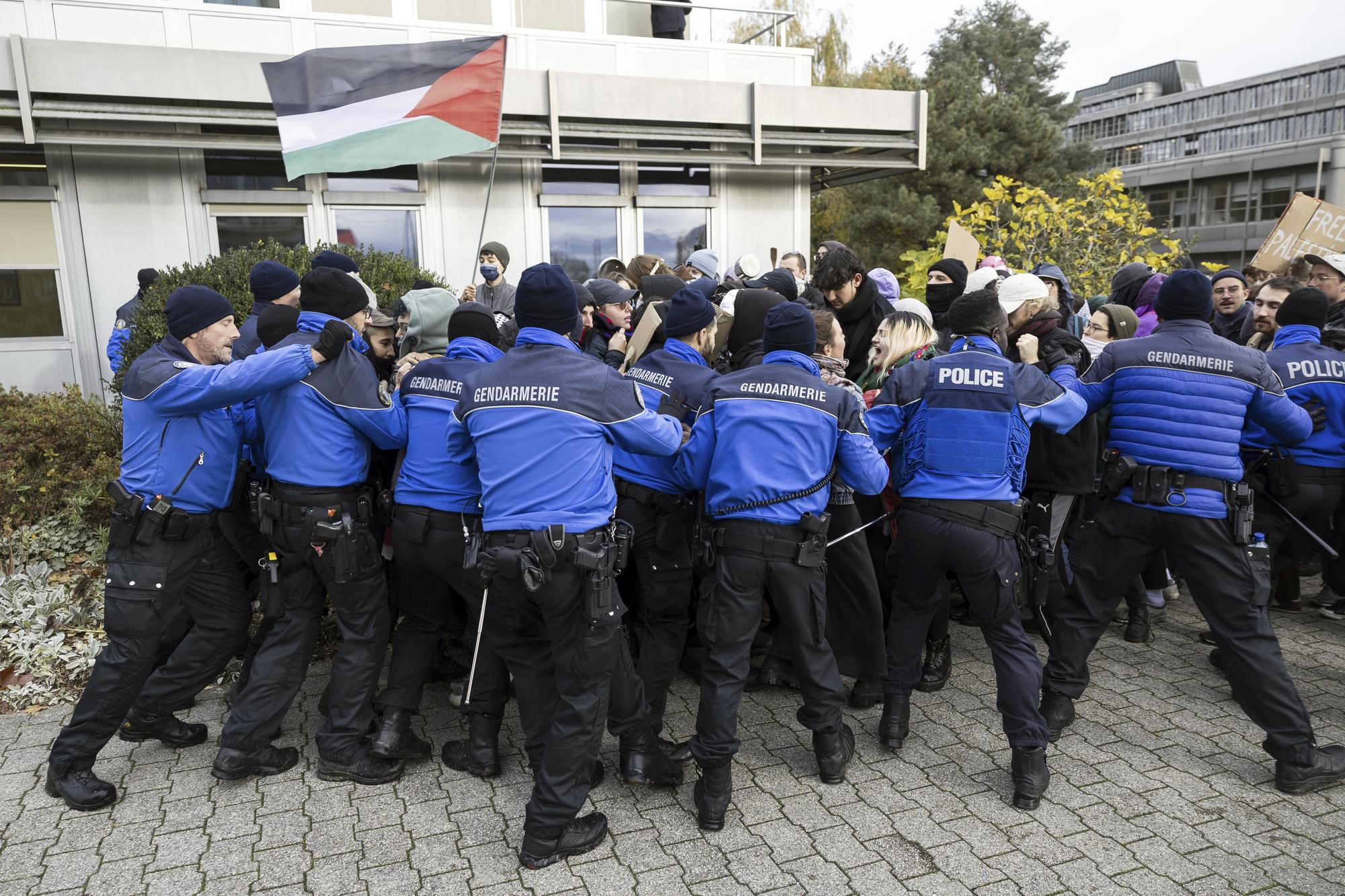 Police scuffle with protesters holding up placards on the situation of the Israel-Hamas war during a demonstration during the visit of French President Emmanuel Macron and Swiss President Alain Berset to the University of Lausanne (UNIL), Switzerland, Thursday, Nov. 16, 2023. Macron is in Switzerland for a two-day visit. (Cyril Zingaro/Keystone via AP)