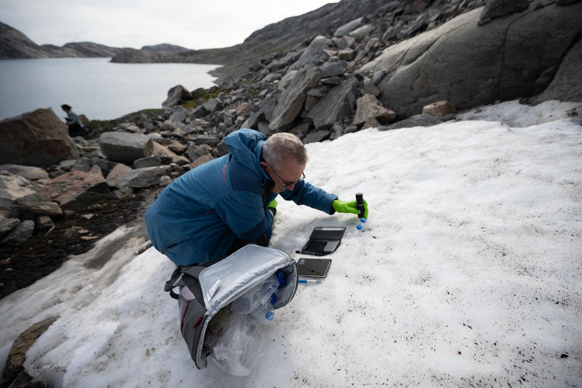 Director of Research at the French National Centre for Scientific Research (CNRS), biologist Eric Marechal, studies layers of algae in the snow near the glaciers around Milne Land in the Scoresby Sound Fjord, Eastern Greenland on August 14, 2023. The French National Centre for Scientific Research is undertaking an expedition to explore Greenland's isolated fjords, the planet's largest fjord system, which remains vastly understudied. The expedition, arranged by the volunteer-run French initiative Greenlandia, is dedicated to understanding the climate change's effects on Scoresby Fjord and its inhabitants. (Photo by Olivier MORIN / AFP)